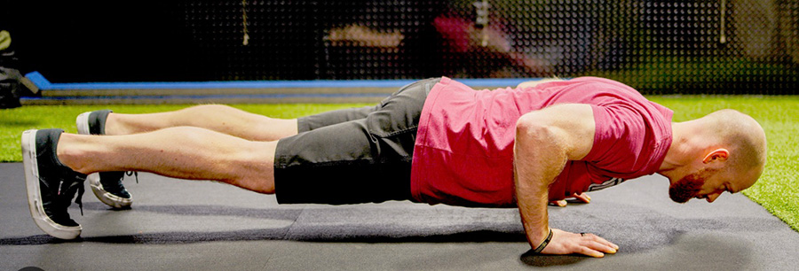 Physical trainer showing the proper form at the bottom or a push up. 